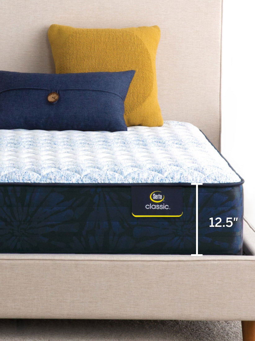 Corner of classic medium mattress with 2 pillows(gold and blue) on top of it showing the size with a white ruler showing the size of 12.5"