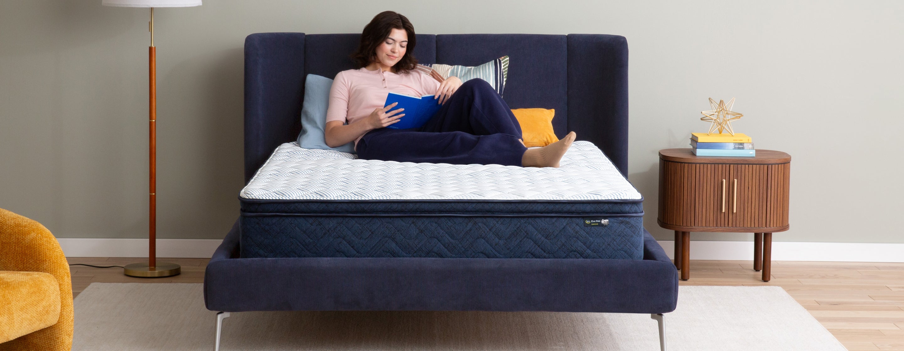 Woman laying on top of a Serta Mattress in Box reading a book.