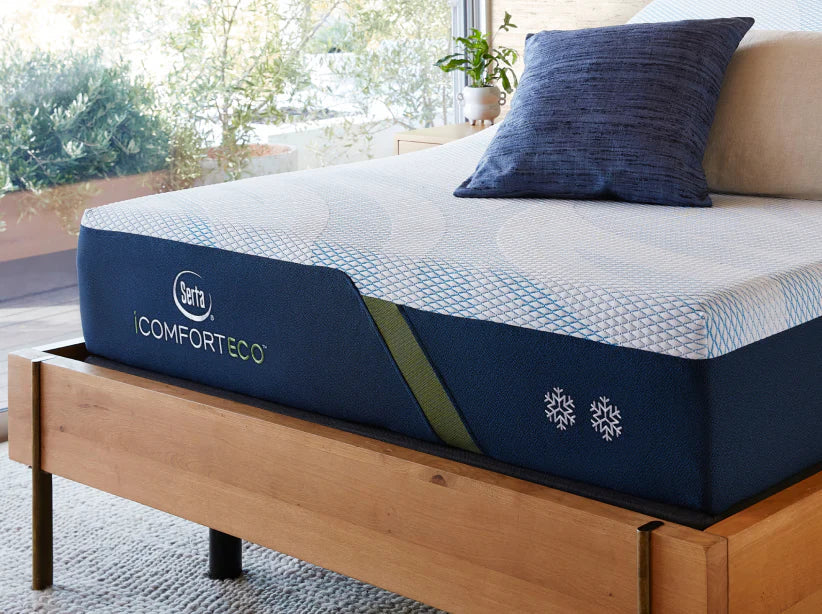 iComfort Eco mattress with 2 pillows on top of it placed in a brown bed frame.