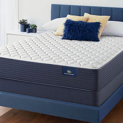 The Serta Classic Firm 10.5" in a bedroom, on a blue bed with blue pillows