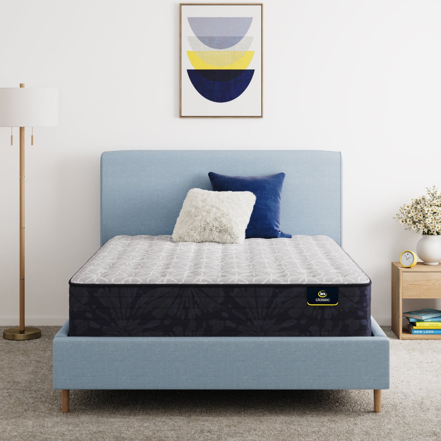 Serta Classic Clarks Hill Mattress on a bed with a blue headboard and decorative pillows in a bedroom setting.
