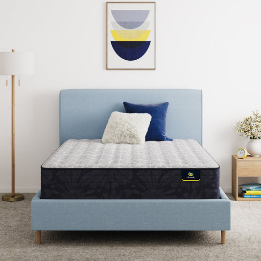 Serta Classic Clarks Hill Mattress on a bed with a blue headboard and decorative pillows in a bedroom setting.