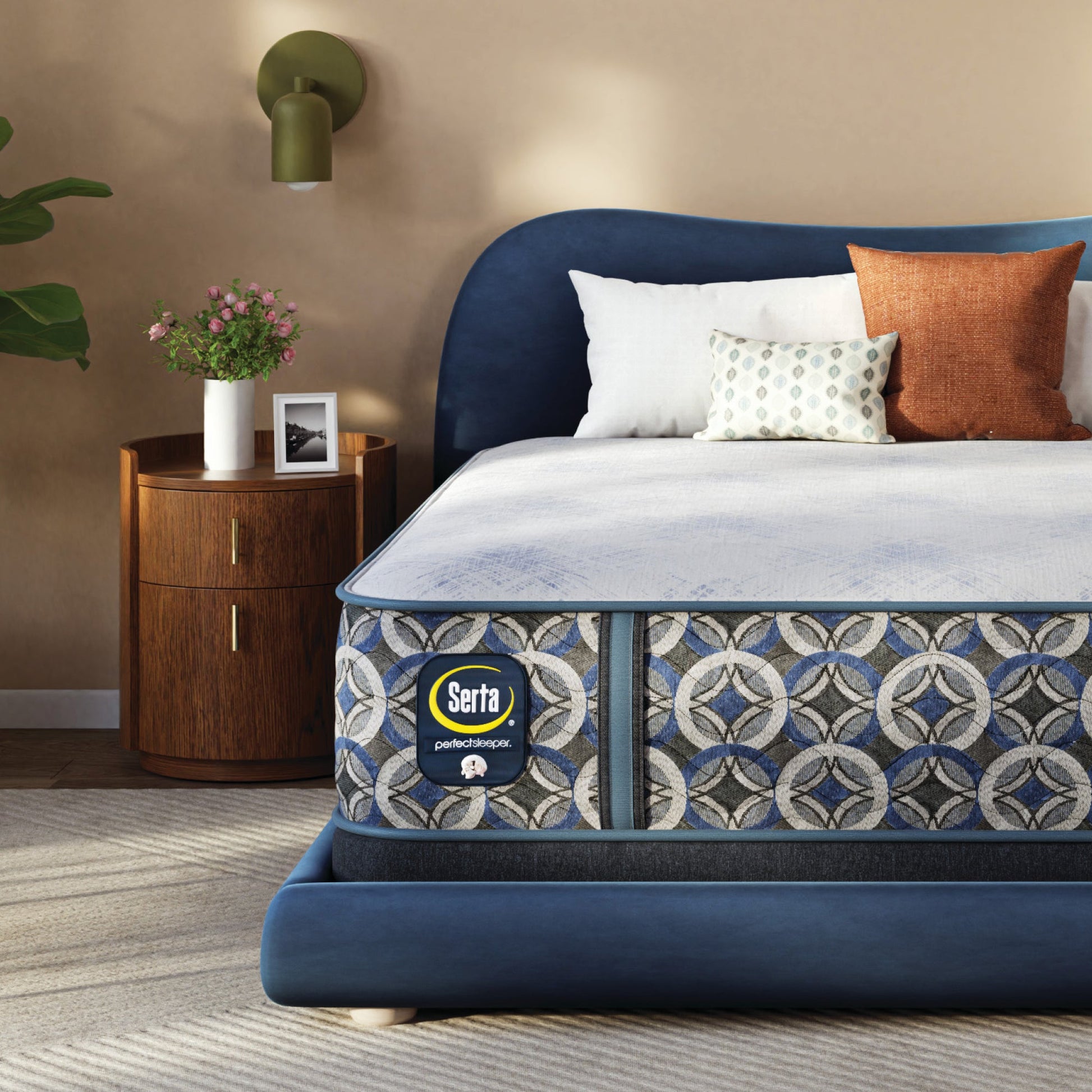 Bed with blue headboard and patterned Serta Perfect Sleeper Hybrid Firm  mattress in a bedroom setting.