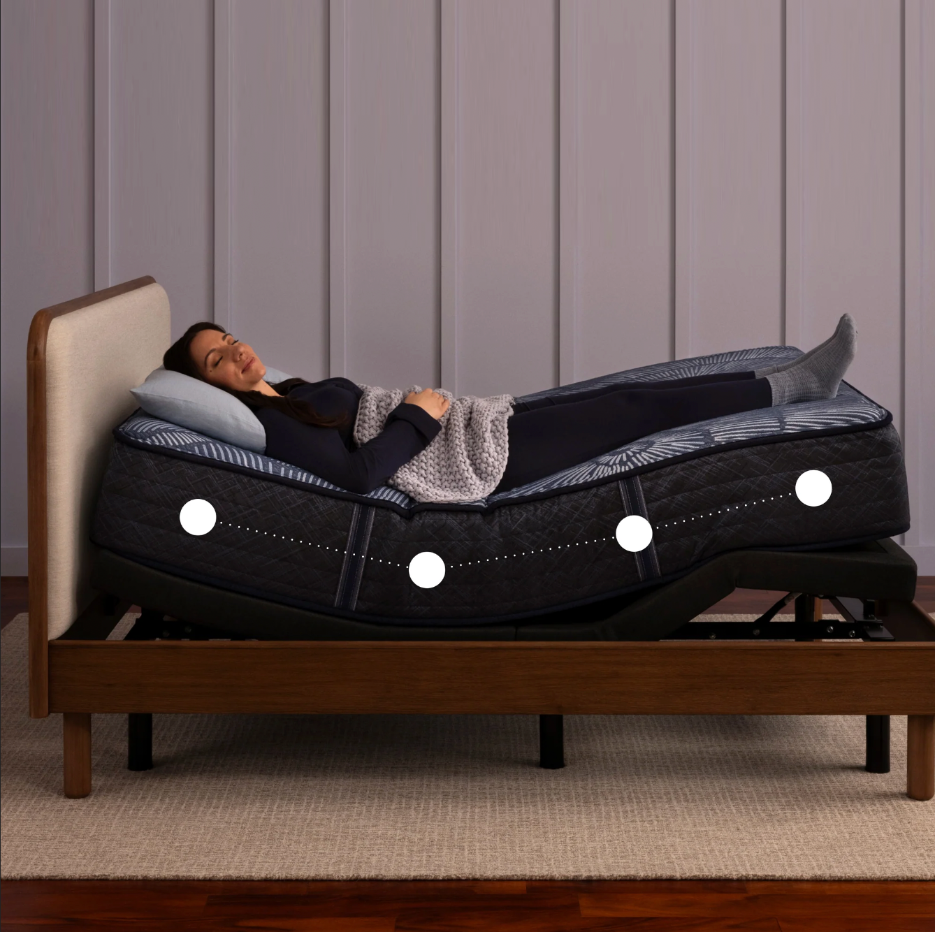 Woman reclining on a Serta adjustable bed with a mattress that contours to her body, highlighting customizable support and comfort zones.